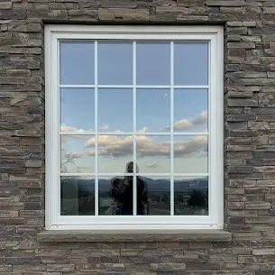 Freshly cleaned grid window on a stone-faced Salt Lake Valley home, sky reflected in the glass