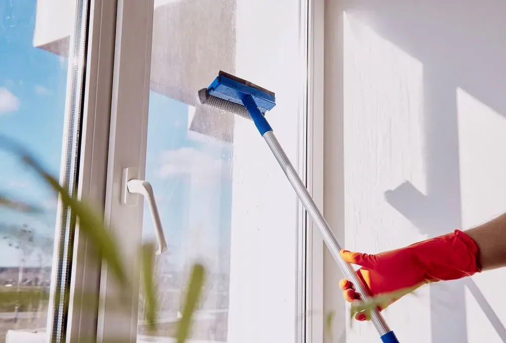 Squeegee pulling clean water down a sunlit window pane
